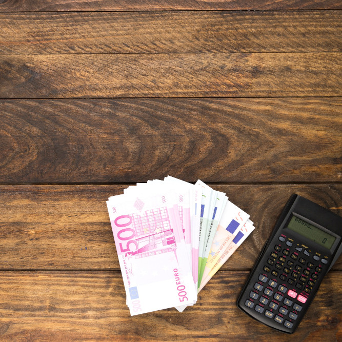 banknoty i kalkulator leżące na biurku