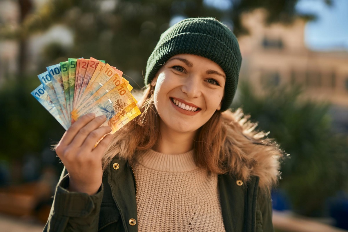 uśmiechnięta kobieta trzyma w ręce pieniądze w obcej walucie